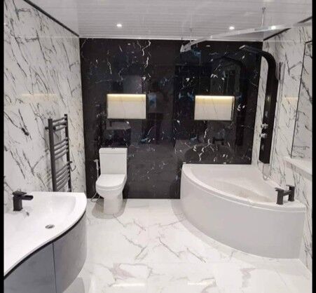 Marble-effect bathroom with a corner bath, black feature wall and heated towel rail