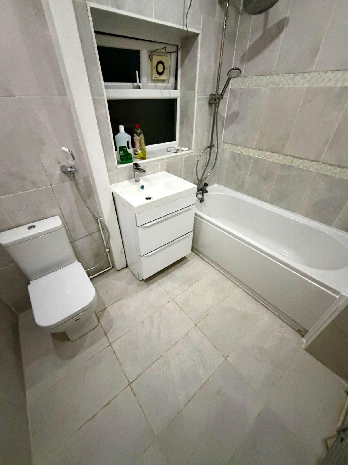 Renovated bathroom with a white vanity unit, WC and grey tiling