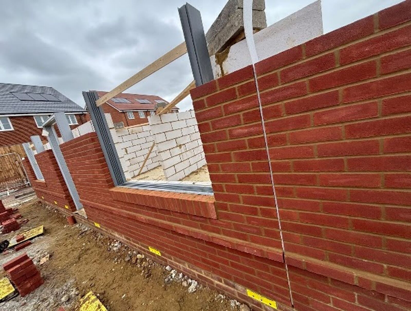 Red-brick extension walls going up around a steel frame and a new window opening