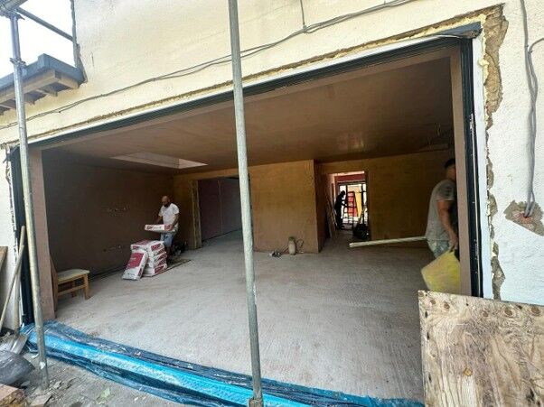 Rear extension shell opened up to the house, with builders working inside