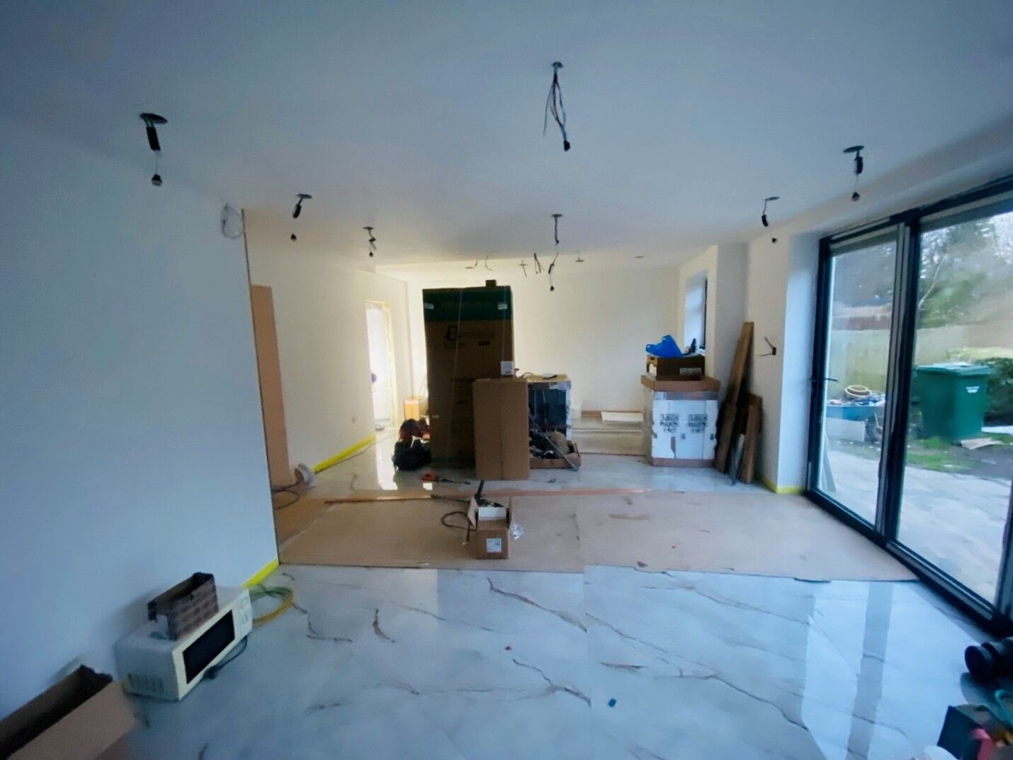 Open-plan extension interior with polished marble-effect floor tiles and sliding glass doors