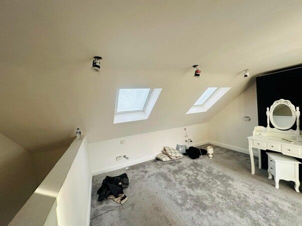 Finished loft conversion room with roof windows and a stair balustrade