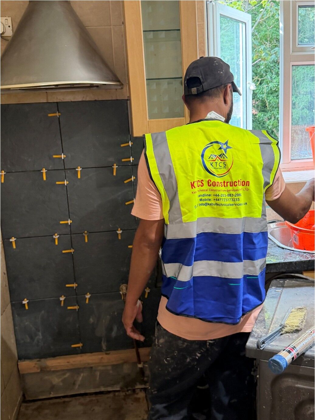 KTCS tiler fixing dark marble-effect kitchen wall tiles with levelling clips