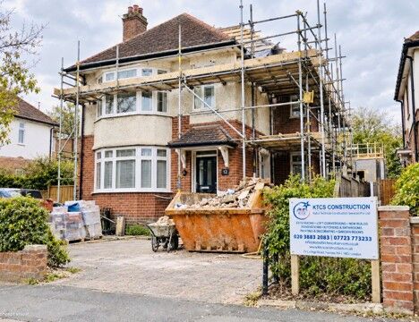 Semi-detached house under scaffolding with a skip and a KTCS Construction site board