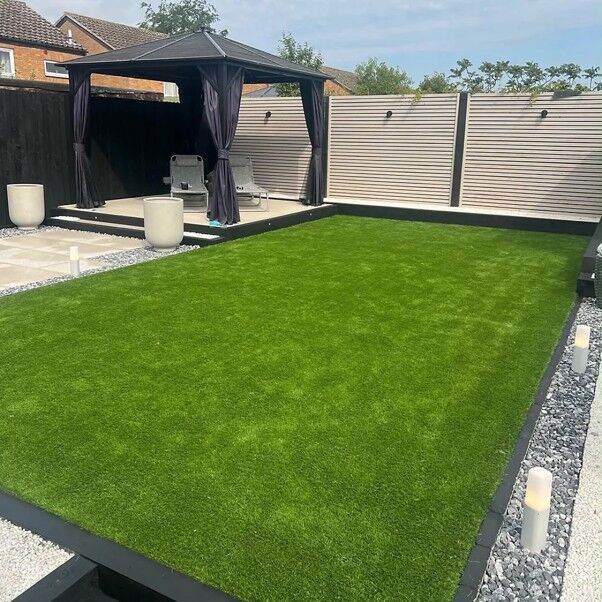 Artificial lawn with grey edging, gravel borders and a raised patio with a gazebo