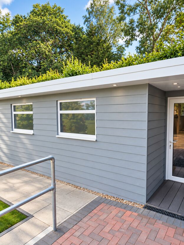 Grey-clad garden room with an access ramp, handrail and block-paved path