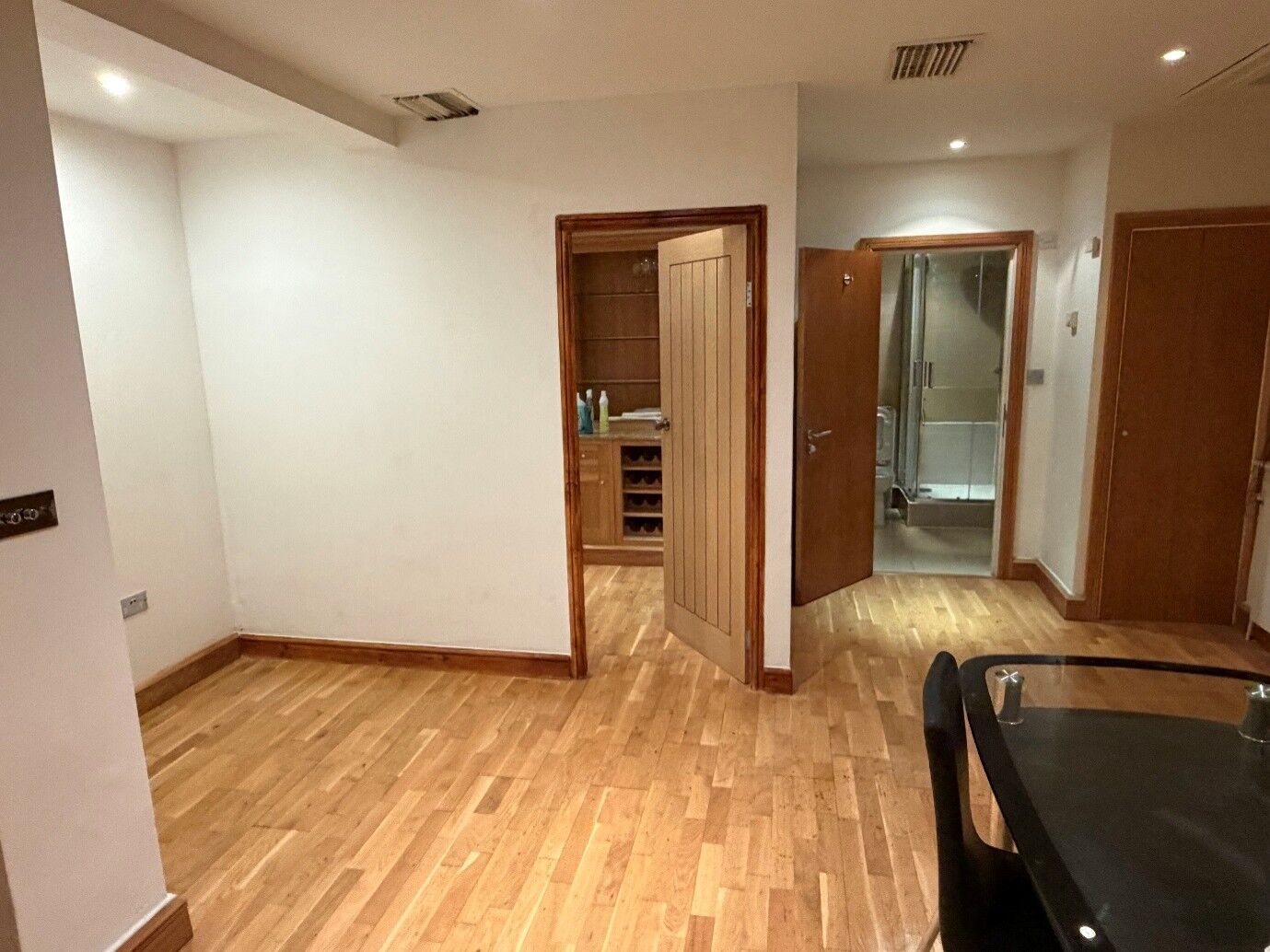 Hallway painted white with wooden doors and oak flooring