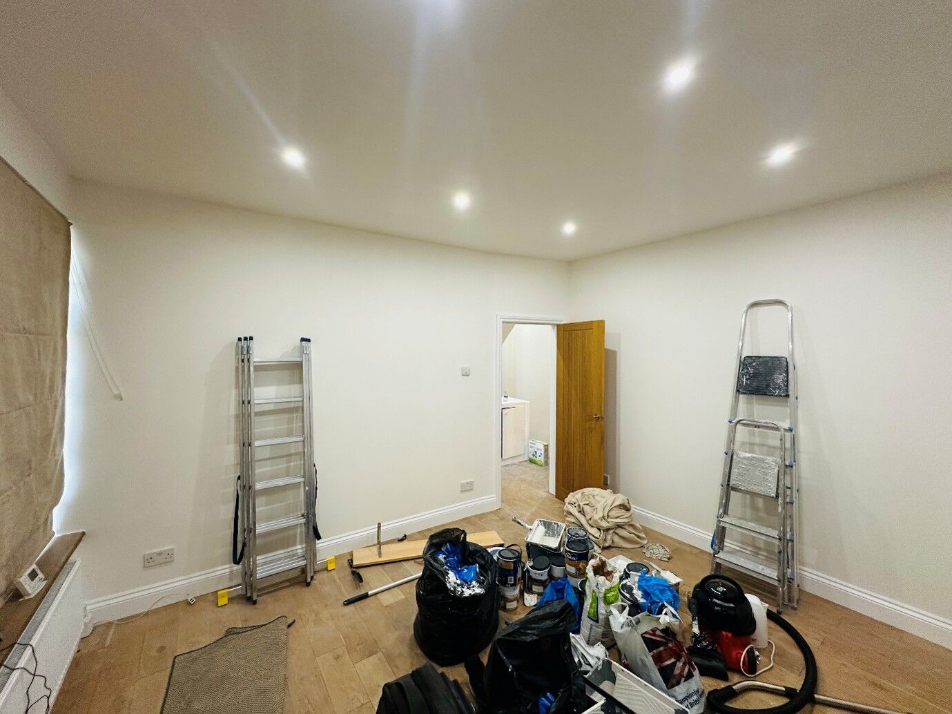 Room painted white with decorating equipment and stepladders in place