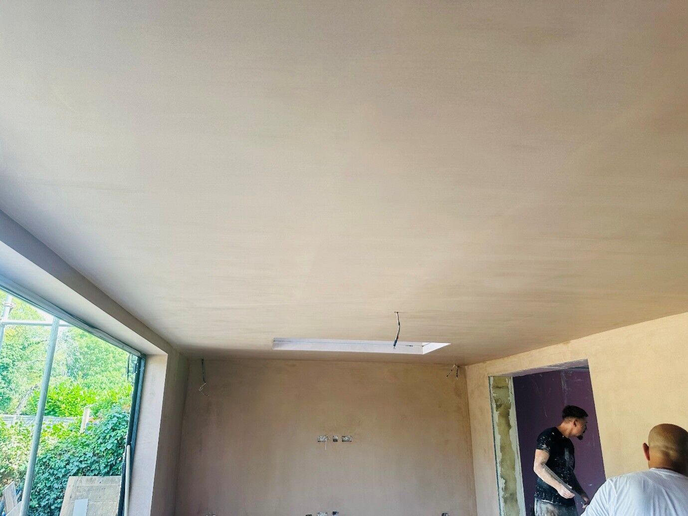 Plastered ceiling in a new extension, with plasterers finishing the room